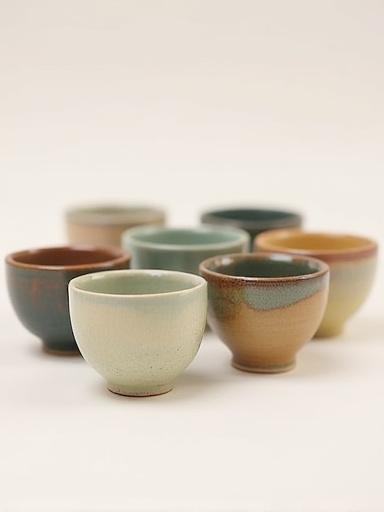 En samling små, unike mokkakopper med varierende glasurer.